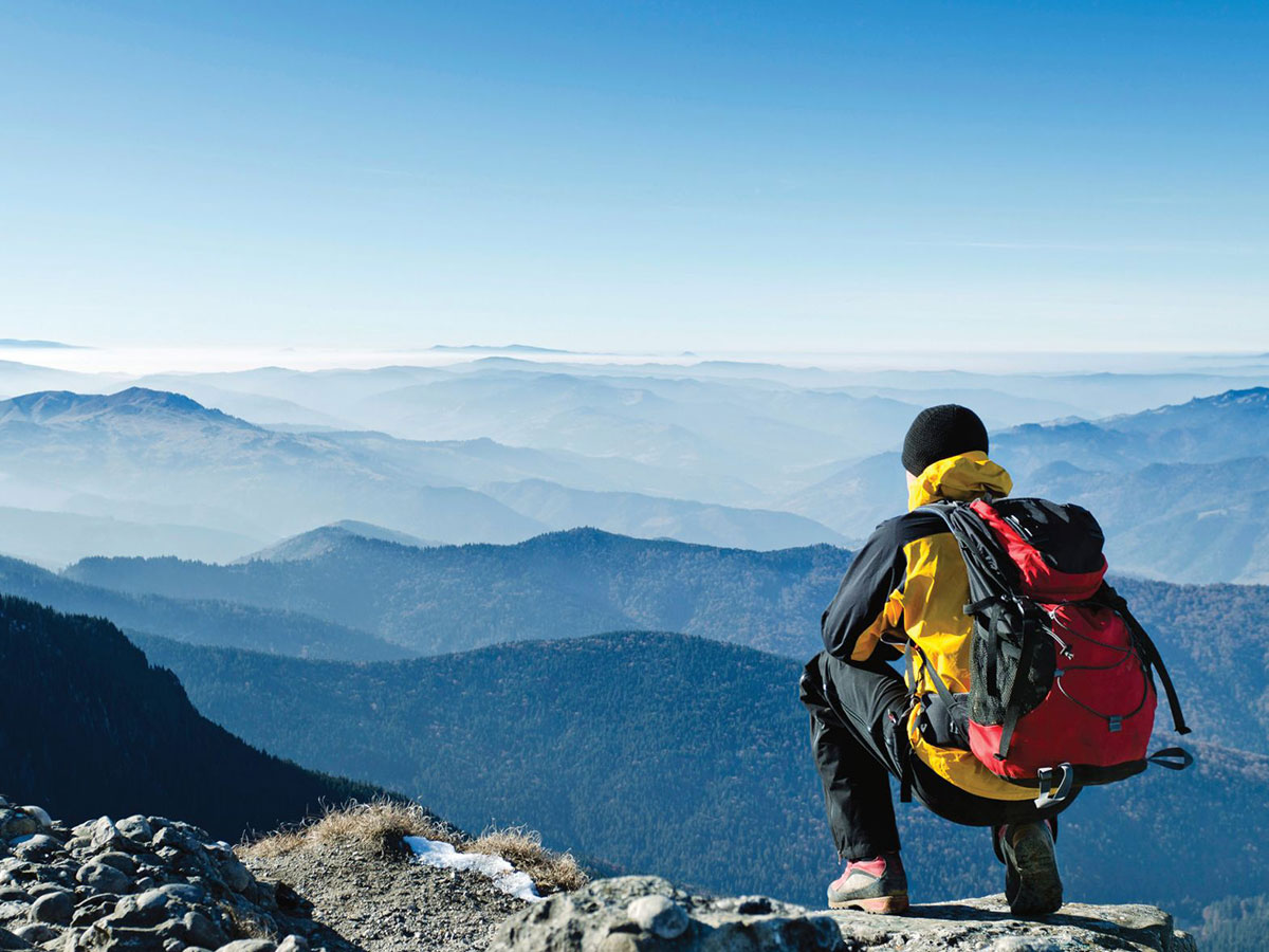 Hiker kneeling at the top of a mountain